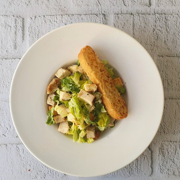 Ensalada César con Pollo Asado y un trozo de pan
