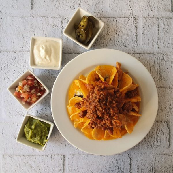 Plato de Nachos con carne junto con tres dips y jalapeños