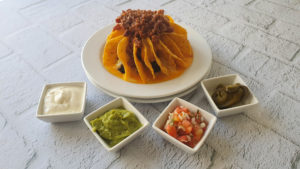 Plato de Nachos con carne junto con tres dips y jalapeños