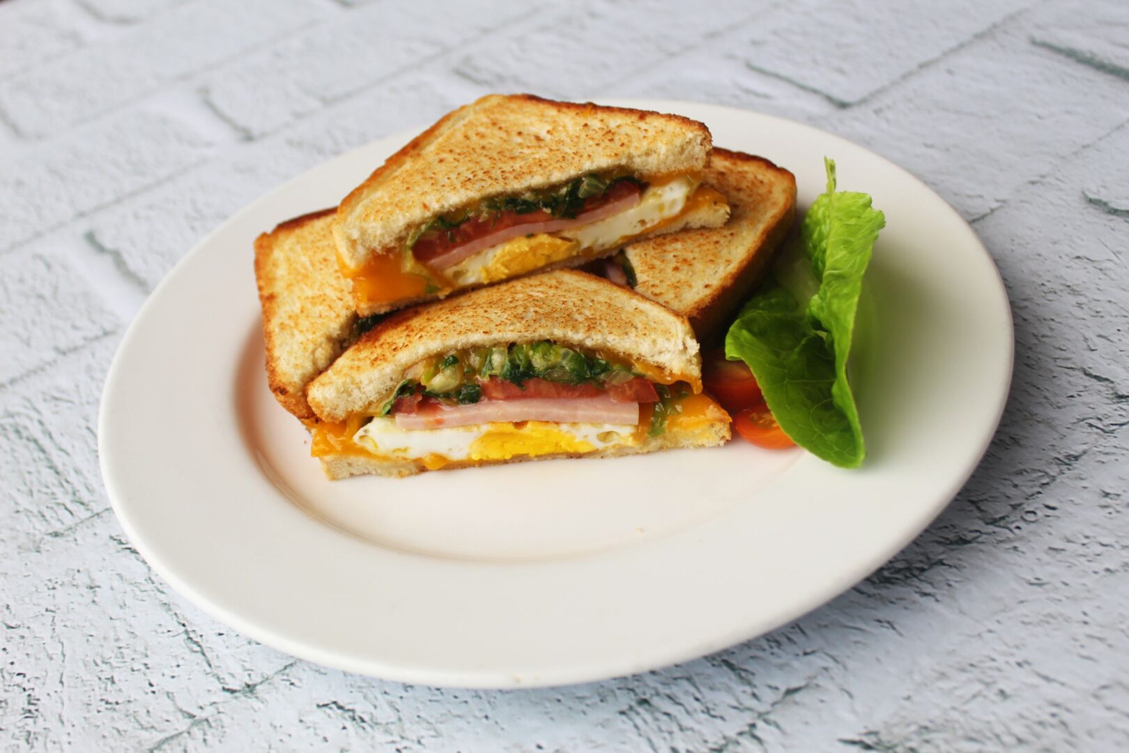 sandwich de huevo con queso en plato blanco