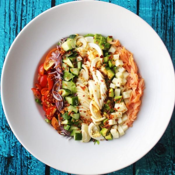 Plato de Ensalada Cobb con salmón ahumado en fondo azul