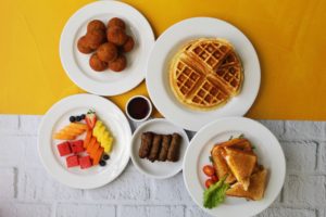 Desayuno con wafles, emparedados, frutas frescas, salchichas y muffins de zanahoría