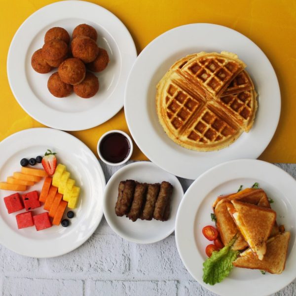 Desayuno con wafles, emparedados, frutas frescas, salchichas y muffins de zanahoría