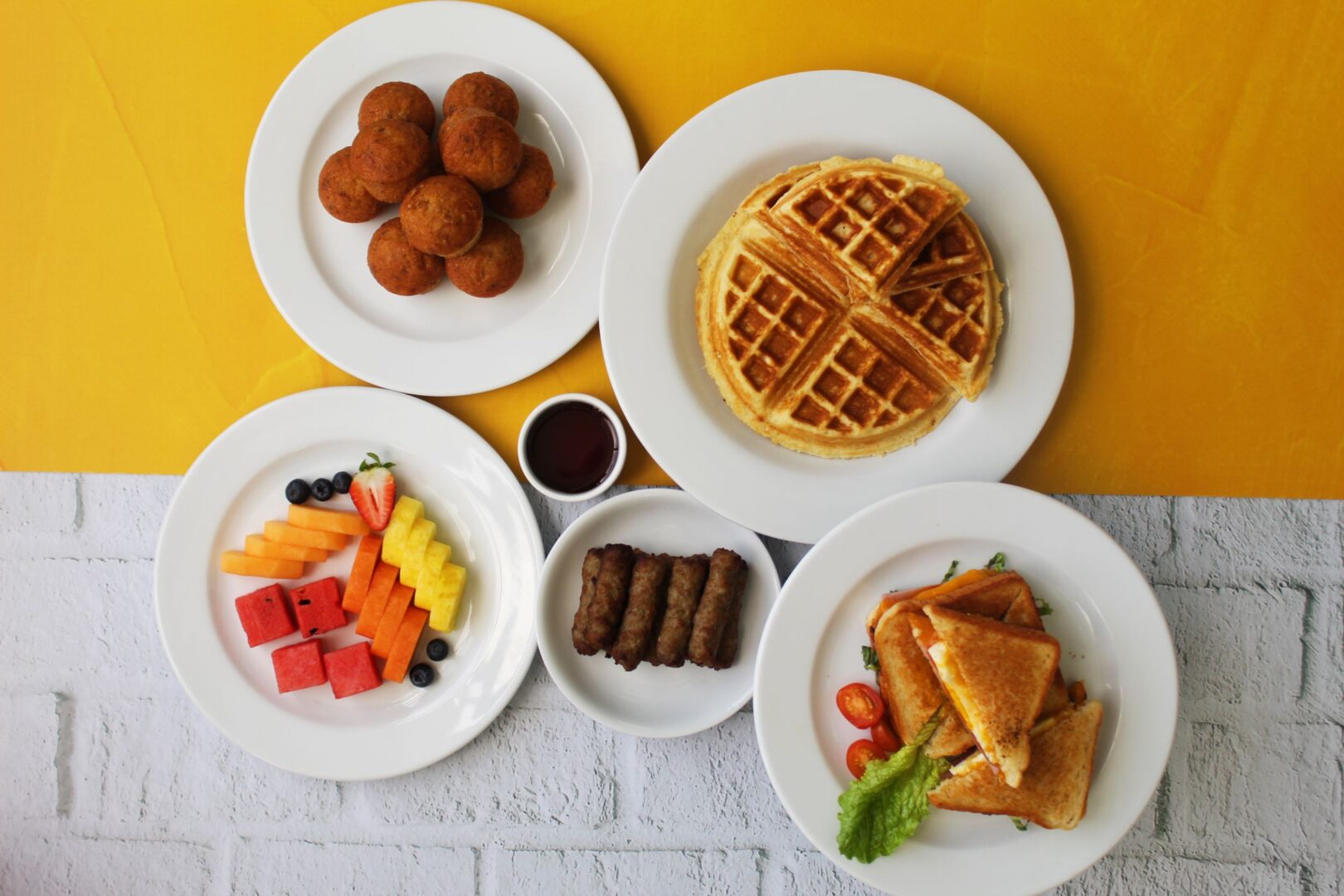Desayuno con wafles, emparedados, frutas frescas, salchichas y muffins de zanahoría