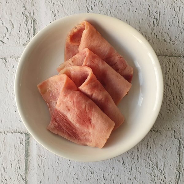Cuatro rebanadas de jamón en plato blanco